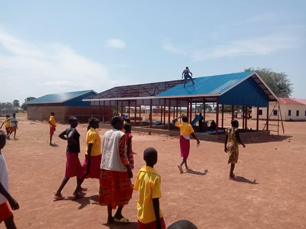 Pupils outside new classrooms built with the community